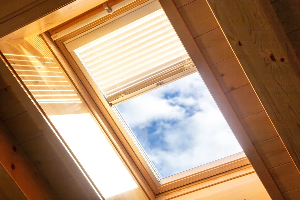 Intérieur d'une maison sous combles avec fenêtre de toit ouverte laissant entrer la lumière naturelle