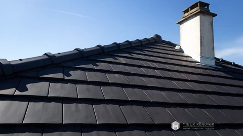 Toiture en pente raide recouverte de tuiles plates en b&eacute;ton coloris anthracite/ardoise, dispos&eacute;es en rang&eacute;es r&eacute;guli&egrave;res avec recouvrement