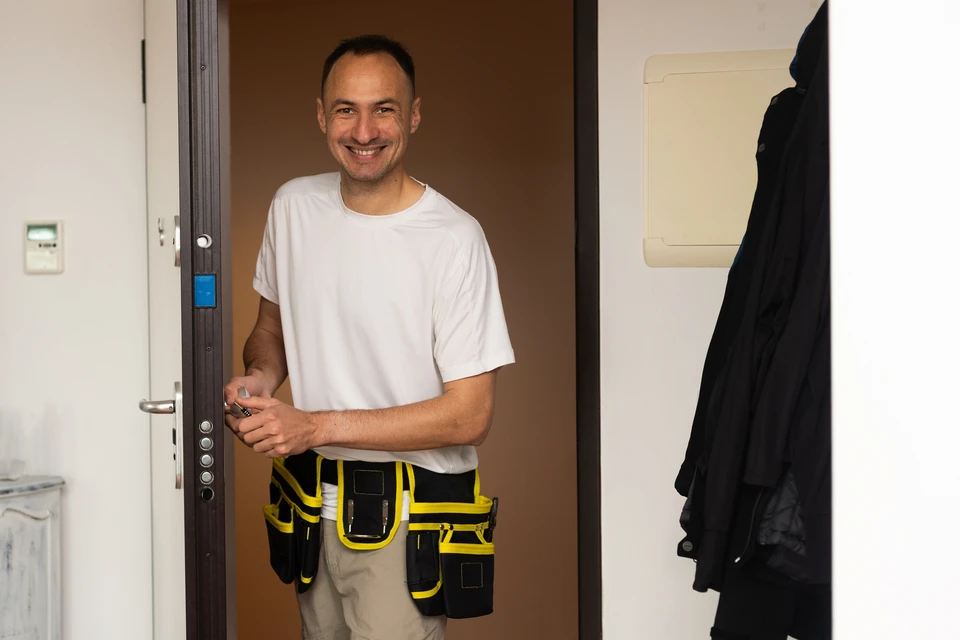 Main tenant les clés d'une maison avec porte-clés en forme de maison en bois