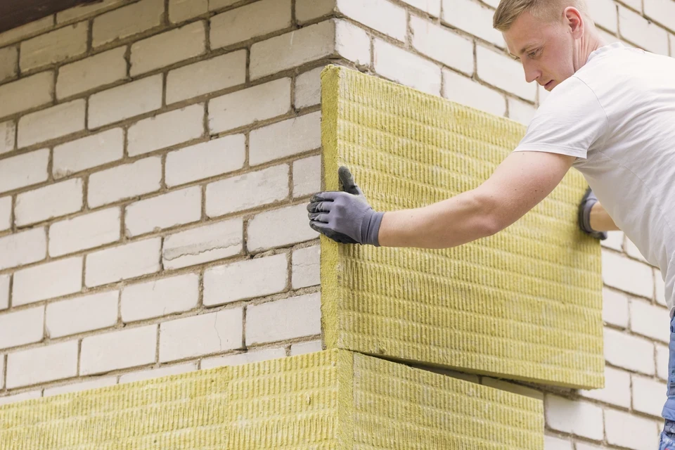 Chantier de construction ext&eacute;rieur avec ouvriers en gilets haute visibilit&eacute; jaune et orange installant l'isolation et la couverture d'une toiture en pente
